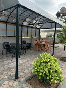 a pavilion with tables and chairs and a table and a bush at Hotel Lile in Ureki