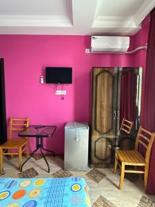 a room with a pink wall with a bed and a table at Hotel Lile in Ureki