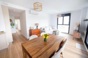 Il dispose d'une cuisine et d'un salon avec une table et des chaises en bois. dans l'établissement Gandia Playa Moderna - nuevo con piscina y parking, 2 banos, playa 300 m, grau 300 m, à Playa de Gandia
