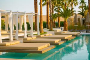 a pool with palm trees and umbrellas at UNA HOTELS MH Matera in Matera