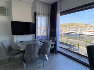 a dining room with a table and chairs and a large window at Marina Guest House in Çeşme