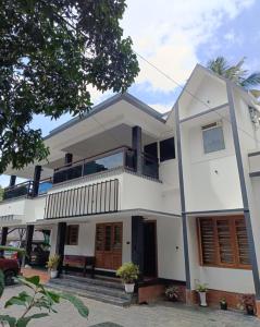 a large white house with a balcony at Cozy munnar home stay in Anachal