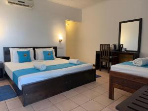 una camera con 2 letti, una scrivania e uno specchio di Hotel Coral Bay a Trincomalee