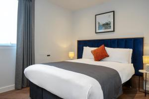 a bedroom with a large bed with a blue headboard at Station Suites Aparthotel in Middlesbrough