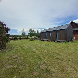 a building in a field with a grass yard at Brzozowe Ostrowie in Kozłowo +27 photos
