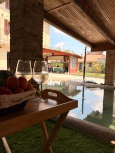 two glasses of wine on a table next to a pool at ByVigin in Magliano Alfieri