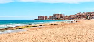 a beach with people walking on the sand and the ocean at Relax & Sea Apartment - Cabo Cervera - Torrevieja in Torrevieja +46 photos