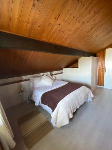 a bed in a room with a wooden ceiling at Appartement vue lac in Publier