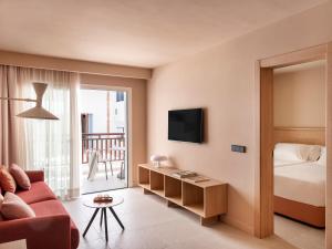 salon z czerwoną kanapą i łóżkiem w obiekcie Inturotel Esmeralda Park w mieście Cala d´Or