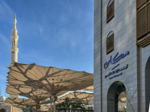 a building with an umbrella in front of a mosque at Makarem Haram view suites in Al Madinah