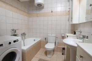 a bathroom with a toilet and a sink and a washing machine at The Blue Horizon House in Afitos