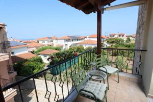 a balcony with two chairs and a view of a city at The Blue Horizon House in Afitos