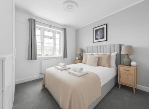 a white bedroom with a large bed and a window at Spacious House with Garden in London