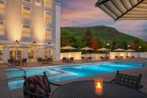 un hotel con piscina, mesas y sillas en North Conway Grand Hotel en North Conway