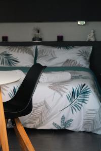 a bed with white sheets and green leaves on it at OCEAN 53 cottage avec piscine privée in Lesperon +14 photos