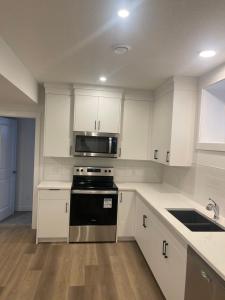 a kitchen with white cabinets and a stove and a microwave at Westminister Manor in YYC