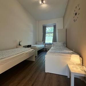 a bedroom with two beds and a window with a clock on the wall at WDI - WorkersSpace in Bochum