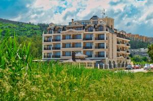 a large building in the middle of a field of grass at Sunny Castle Hotel - All Inclusive, Beach and Free parking in Kranevo