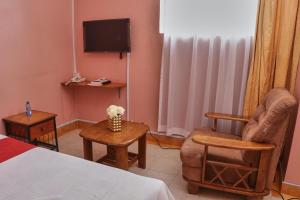 a room with a bed and a chair and a tv at 136 Boutique Address Hotel in Nairobi