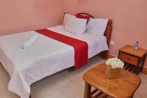 a bed with a red and white blanket and a table at 136 Boutique Address Hotel in Nairobi