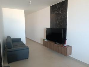 a living room with a chair and a television at Boscolo Flats Nadur - Modern Rooms with private en-suite bathrooms in Nadur
