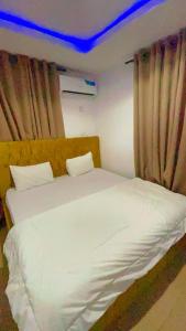 1 cama blanca grande en una habitación con cortinas en Temi40HUS, en Ibadán