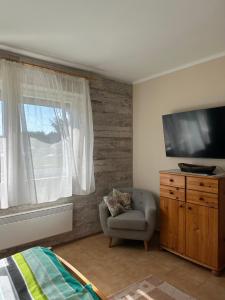 a bedroom with a tv and a chair and a window at Kislőd Apartman in Kislőd