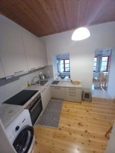 a kitchen with white cabinets and a wooden floor at Sweet Red Home in Asprogerakata