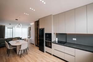 a kitchen with white cabinets and a table with chairs at Skyline penthouse Sarande in Sarandë