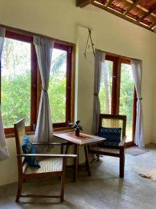 a dining room with a table and chairs and windows at Hello Homestay in Galle