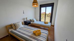 ein Schlafzimmer mit zwei Betten und einem Fenster in der Unterkunft Escapada Slow-Life Piscina, terrazas y olas cerca - Casa Pez in Majanicho + 32 Fotos