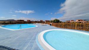 ein großer Pool neben einem Holzzaun in der Unterkunft Escapada Slow-Life Piscina, terrazas y olas cerca - Casa Pez in Majanicho