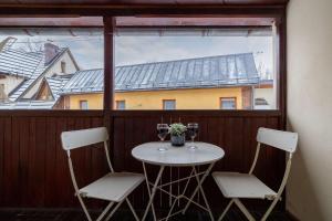 扎科帕内Apartment with Parking close to the Krupówki by Noclegi Renters的阳台上配有两把椅子和一张桌子,阳台上配有酒杯