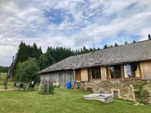 a stone house with a table and chairs in a yard at Apartmány2 - Náhlov in Frymburk