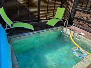 a swimming pool with chairs and a pool noodle in it at Ti caz Désir in Le Tampon