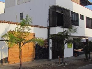 a palm tree in front of a white building at VIVEMAR Bungalow in Punta Hermosa +2 photos