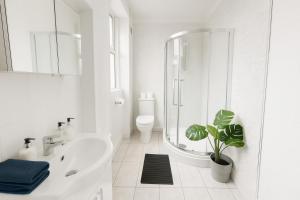 a white bathroom with a shower and a sink at Space For Groups, 10 mins from centre with parking! in Cardiff
