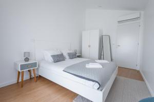 a white bedroom with a large bed and a table at Casa de Penedones - Ventos do Larouco in Penedones +8 photos