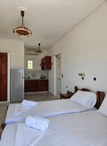 two beds in a white room with a kitchen at Villa Angeliki II in Kámpos +41 photos
