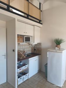 Appartement les flots bleues في فالراس بلاج: مطبخ مع دواليب بيضاء وميكرويف