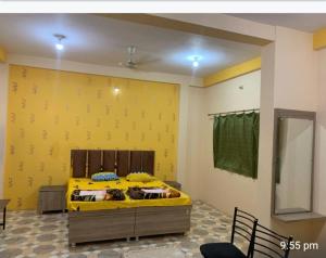 a bed in a room with a yellow wall at Shri Raj Home stay in Ujjain