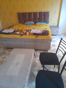 a bedroom with a bed with yellow sheets and two chairs at Shri Raj Home stay in Ujjain