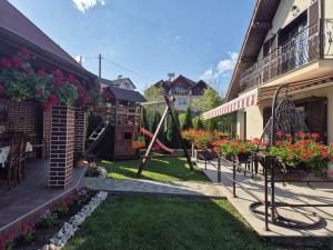 a yard with a swing and flowers on a house at Pensiunea Select in Curtea de Argeş