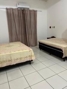 a bedroom with two beds and a tiled floor at Casa simples e conforto in Belém