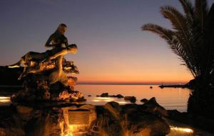 a statue of a man sitting on a rock near the water at JET, luxury appartment 20m from the beach in Kini