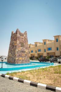 a monument in a parking lot in front of a building at فوج فيو للفلل والشقق الفندقية in Al Namas
