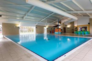 a large swimming pool with blue water in a building at Seascape Holiday Caravan in Tunstall