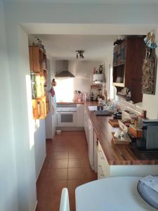 a kitchen with white cabinets and a wooden counter top at Casa da Lameira in Vilar do Ruivo +18 photos