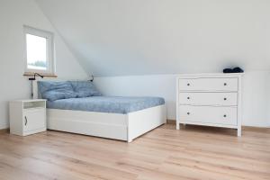 a white bedroom with a bed and a dresser at Ptasi Śpiew in Grzędy