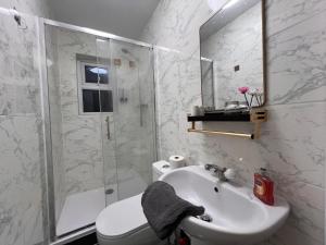 NWIにあるComfy Rooms Close to Airportの洗面台とシャワー付きの白いバスルーム